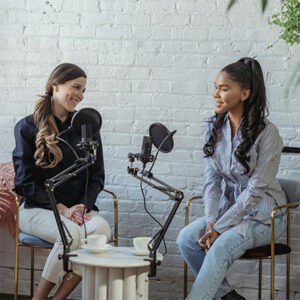 two women sitting and speaking into microphones.