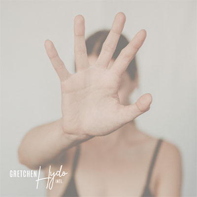 Woman with her hand raised in front of her face in a motion indicating "stop."