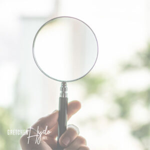 A magnifying glass being held by someone looking into the distance.