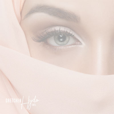 Close up of the eye of a woman wearing a head scarf pulled across her face to cover her mouth and nose.